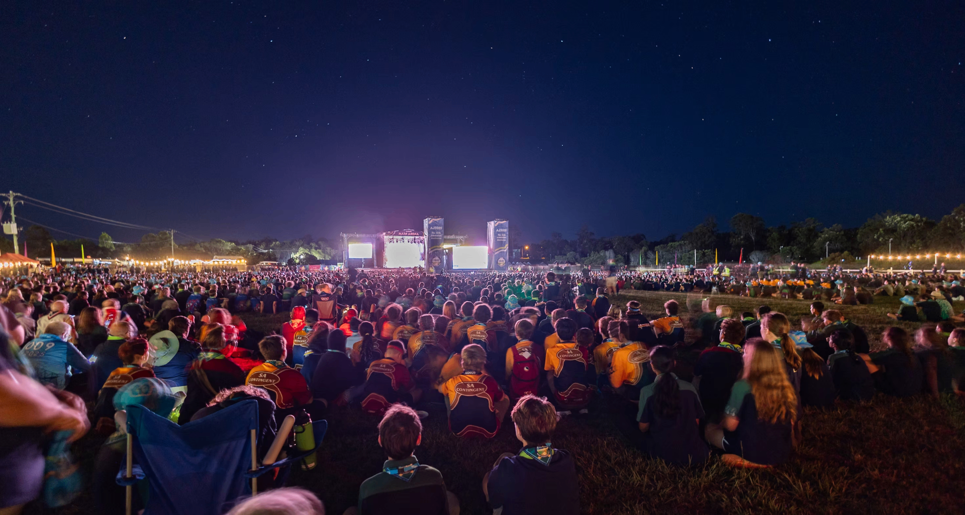 Crowd of Scouts at the AJ2025 main arena under a starry sky